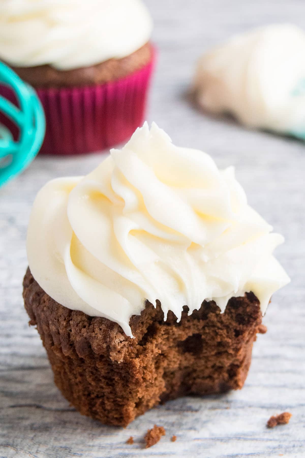 Partially eaten frosted chocolate cupcake. 