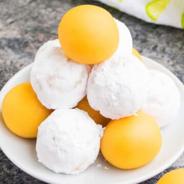 Tower of Lemon Cake Balls or Cake Truffles on white dish where Some are Coated in Powdered Sugar.