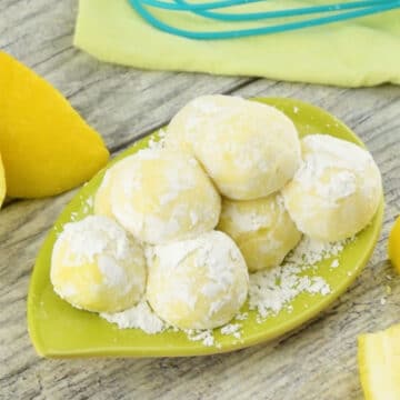 Candy balls coated in powdered sugar on green dish.  