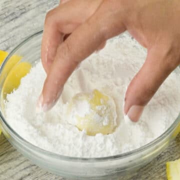 Balls being rolled in a bowl of powdered sugar. 