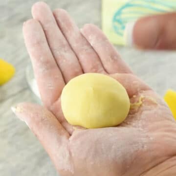 Mixture being formed into small balls with hands. 