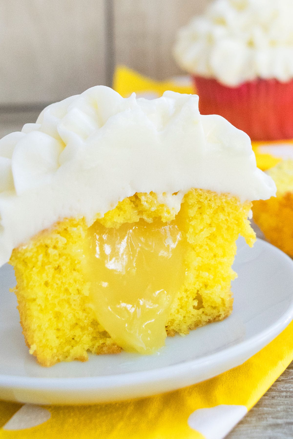 Partially eaten cupcake on white dish with filling oozing out. 