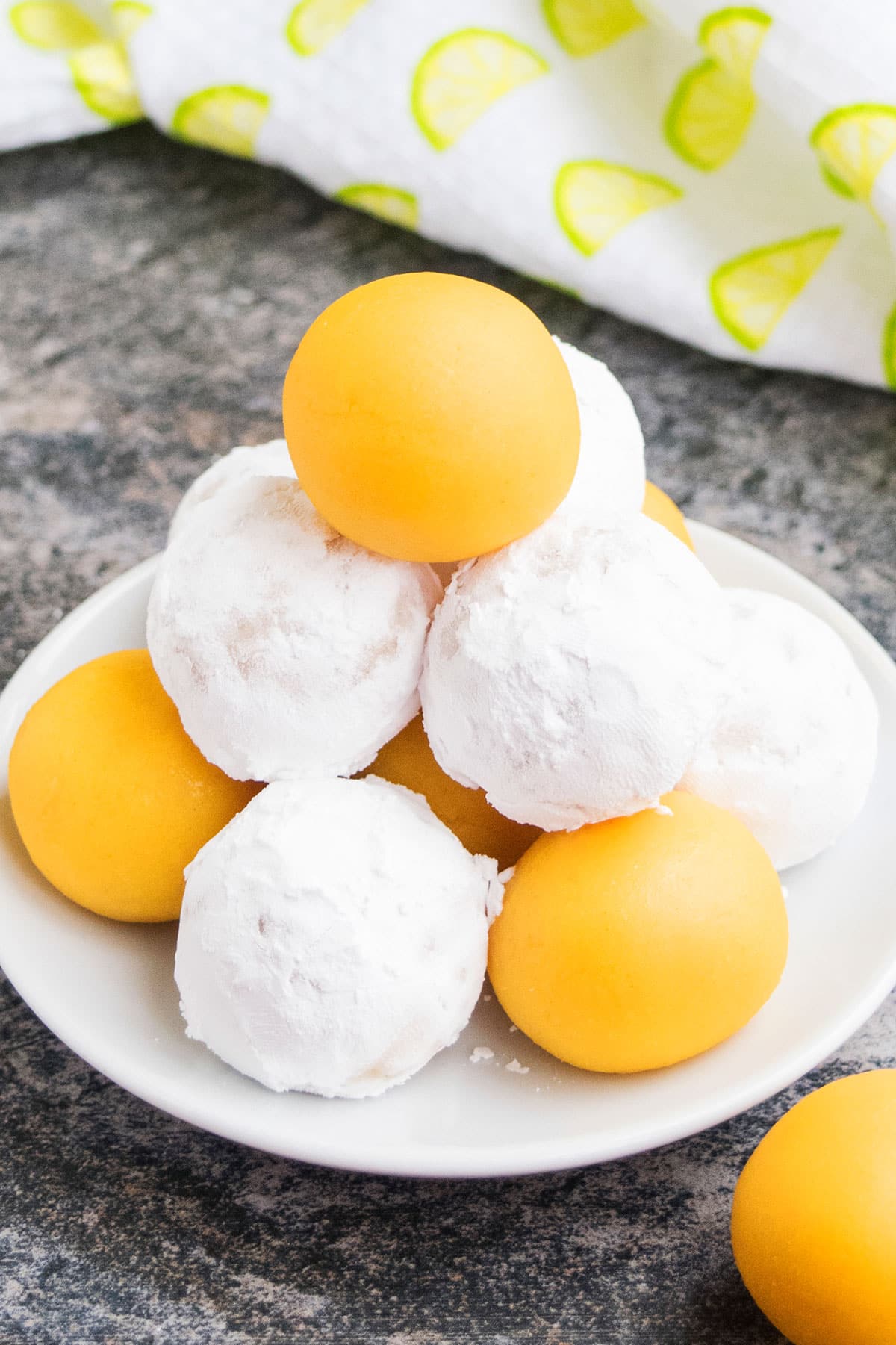 White dish with stack of no bake candy and some are covered in powdered sugar. 