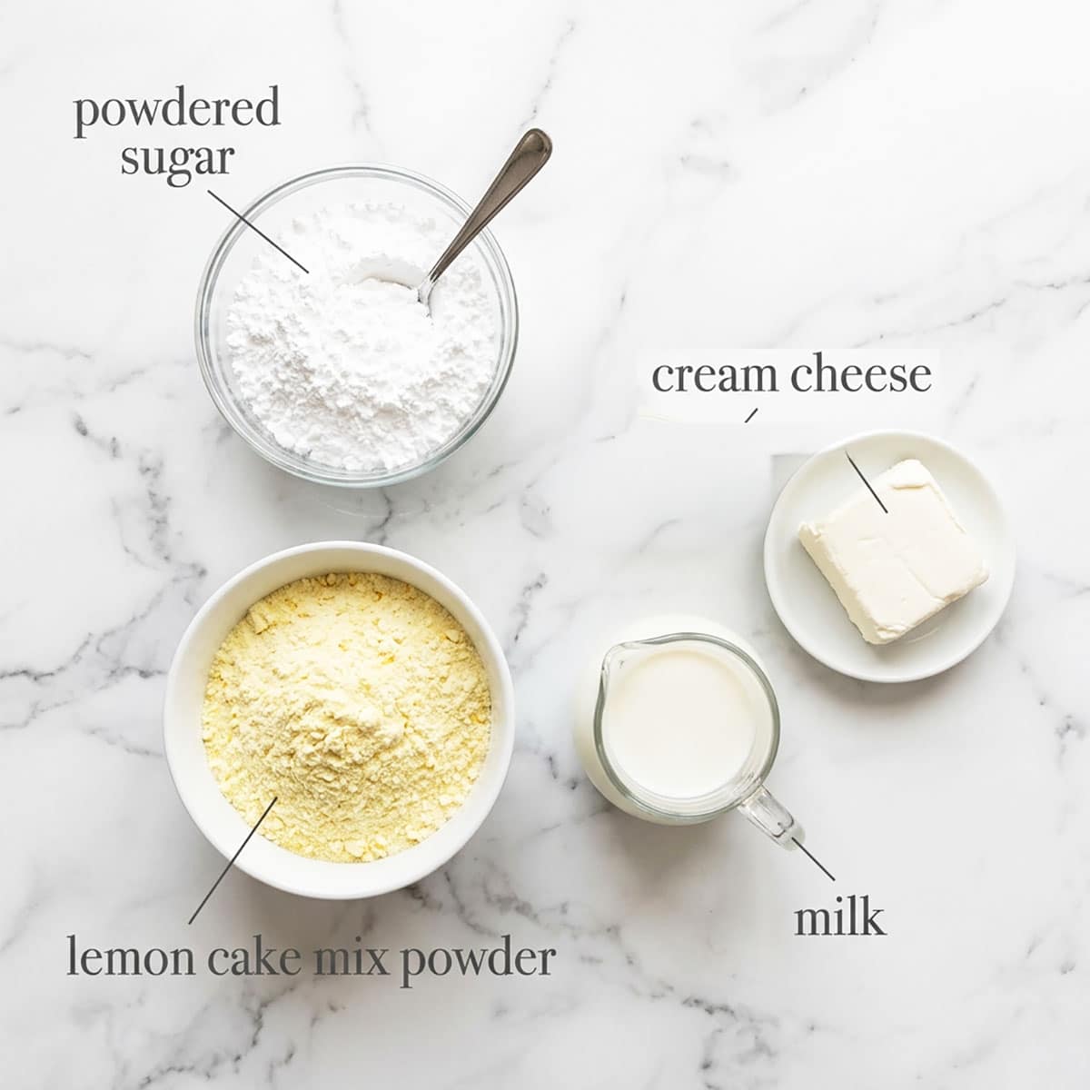 Ingredients for recipe on white marble background- cream cheese, powdered sugar, milk, cake mix. 