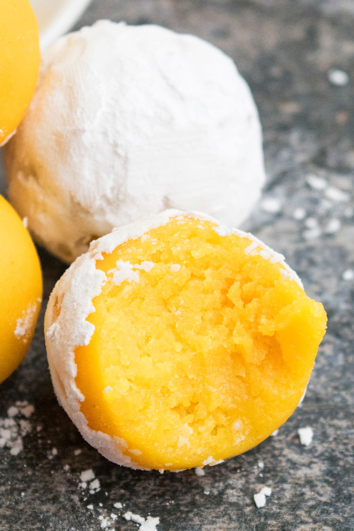 Partially eaten lemon cake truffle on rustic gray background- Closeup shot. 