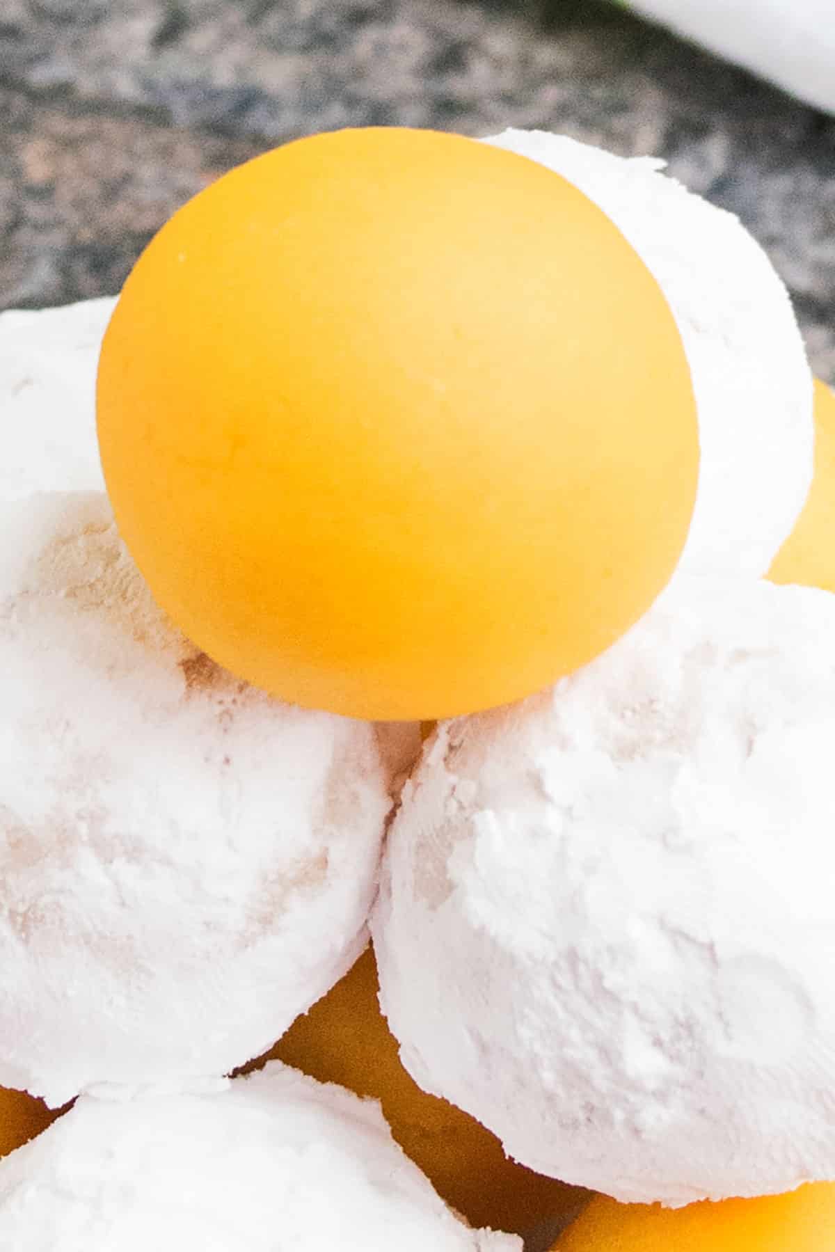 Tower of Lemon Cake Balls With Some Coated in Powdered Sugar.