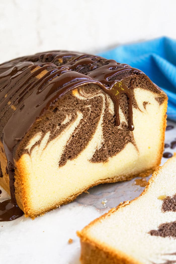 Easy Marble Cake From Scratch With Chocolate Ganache Topping on White Marble Background. 