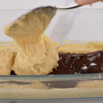 Chocolate cake batter spread on top of vanilla batter and more vanilla batter being spooned on top of that.