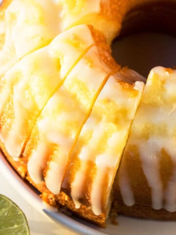 Best easy homemade 7 Up cake with cake mix box and lemon glaze made in bundt pan on white dish and cut into slices.