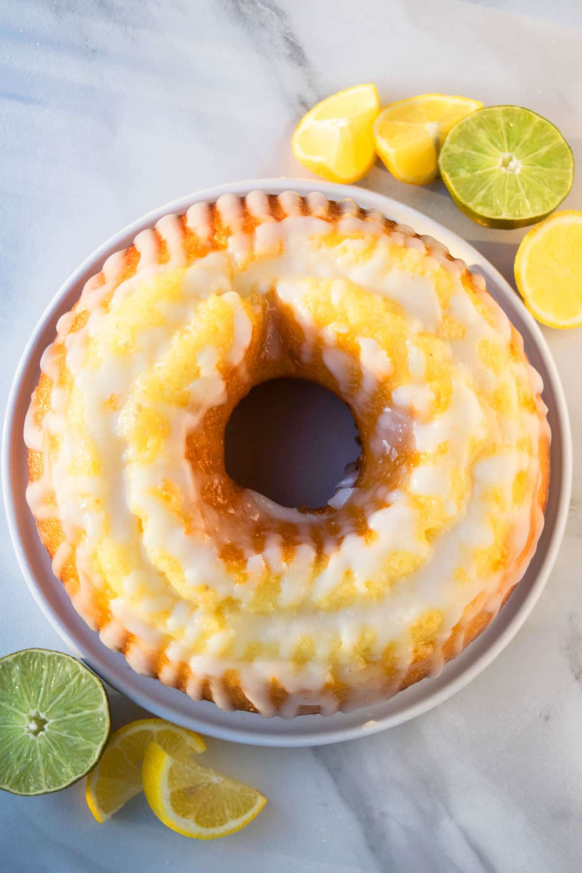 Easy 7 Up cake with cake mix box and lemon glaze made in bundt pan on white dish. 