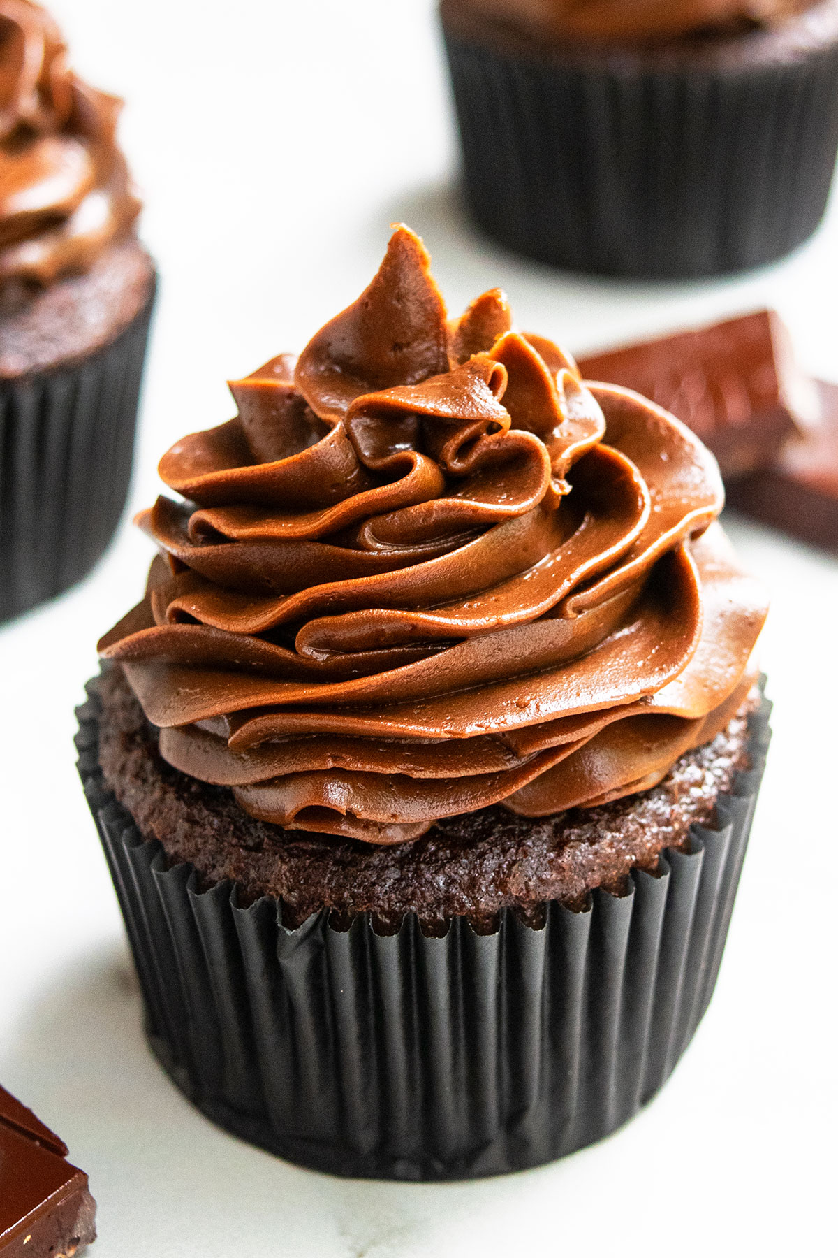 Frosted Soft And Moist Cocoa Cupcakes in Black Liner on White Marble Background.  