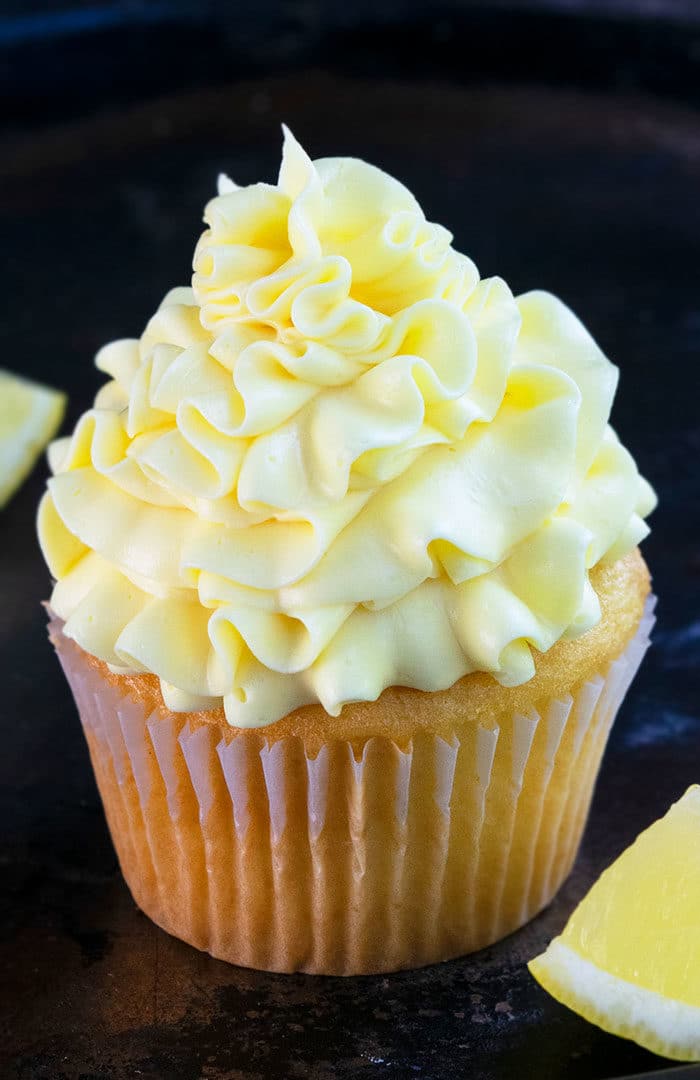 Best Easy Lemon Frosting Swirled on Top of Cupcake on Rustic Black Background