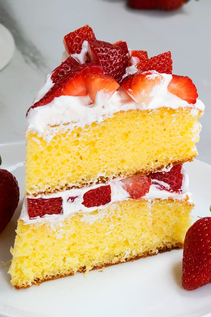 Slice Of Vanilla Cake With Fresh Strawberries and Whipped Cream on White Dish