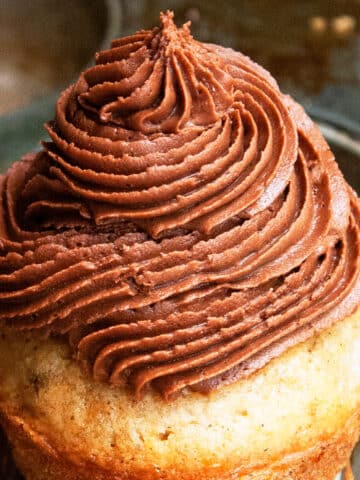 Best Easy Fluffy Chocolate Cream Cheese Frosting with Cocoa Powder Piped on Top of Cupcake.