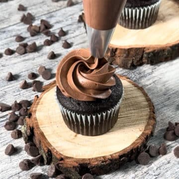 Icing being piped on top of cupcake. 