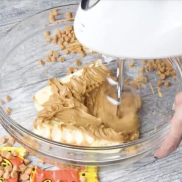 Butter and peanut butter being mixed with hand held mixer. 