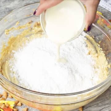 Powdered sugar and heavy milk being added to creamed mixture. 