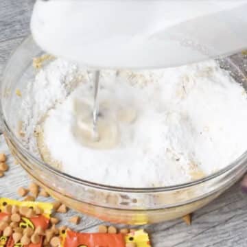 Ingredients being mixed in a glass bowl with hand held mixer. 