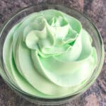 Easy green mint frosting (buttercream) in glass bowl on rustic gray background.