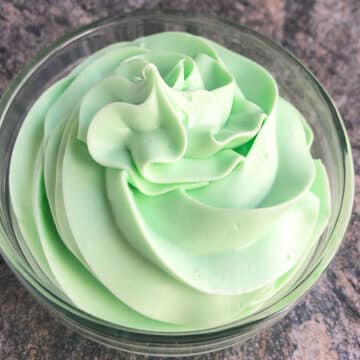 Easy green mint frosting (buttercream) in glass bowl on rustic gray background.