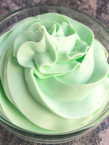 Easy green mint frosting (buttercream) in glass bowl on rustic gray background.
