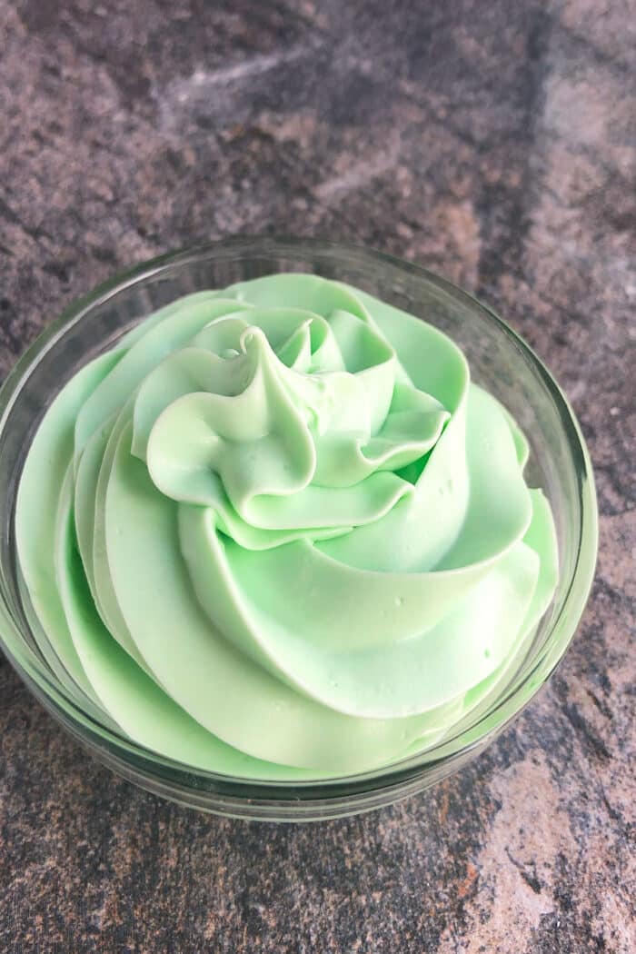 Glass bowl with swirl of green buttercream frosting.