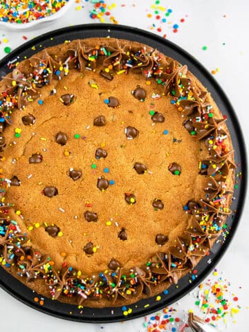 Easy Chocolate Chip Cookie Cake with Chocolate Frosting Served on a Black Plate