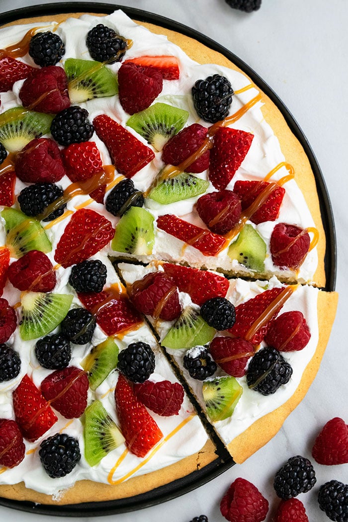 Easy Sugar Cookie Fruit Pizza on Black Plate With A Slice Cut Out