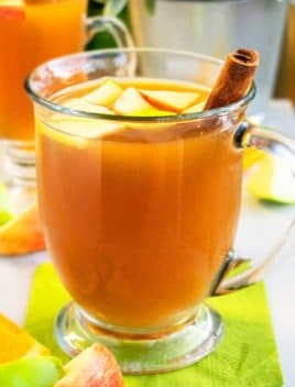 Spiced Hot Apple Cider in Glass Cup with Cinnamon Stick on Green Napkin