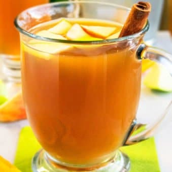 Spiced Hot Apple Cider in Glass Cup with Cinnamon Stick on Green Napkin