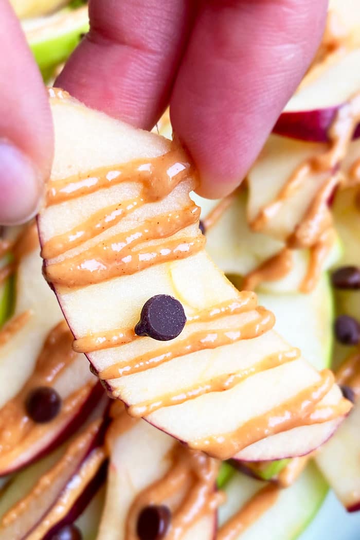 Closeup Shot of Holding an Apple Slice with Peanut Butter and Chocolate Chips