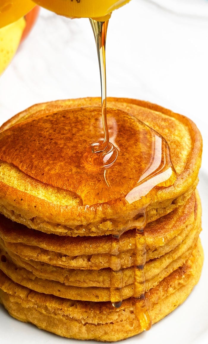 Stack of Easy Pumpkin Pancakes with Maple Syrup Being Poured on Top