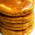 Stack of Pumpkin Pancakes with Maple Syrup Topping on White Plate