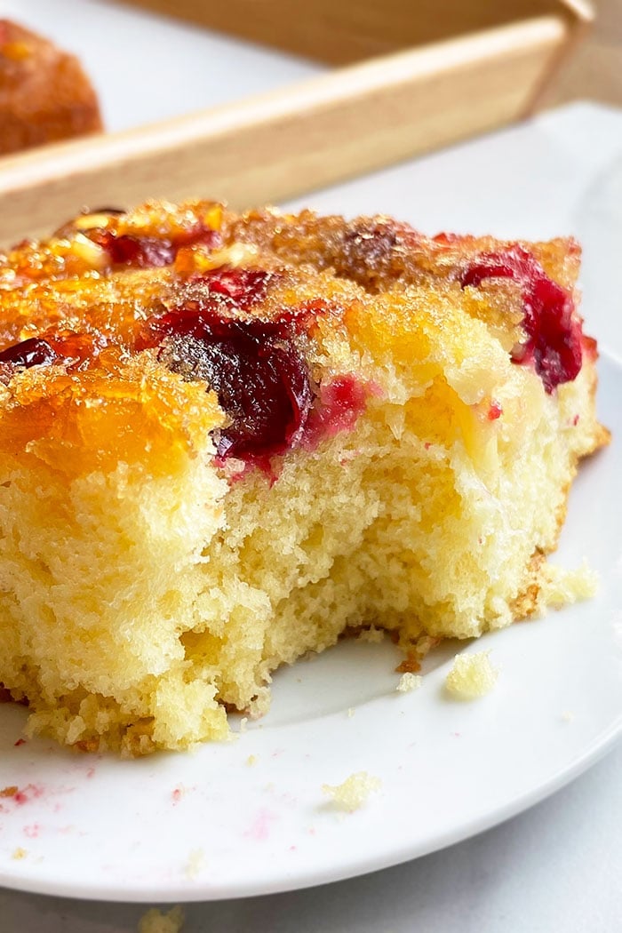 Partial Slice of Upside Down Cake With Cranberries and Pineapples on White Plate 