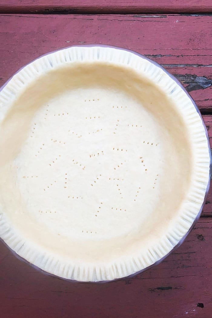 Easy Butter Pie Crust Spread in Pie Dish on Rustic Red Wood Background