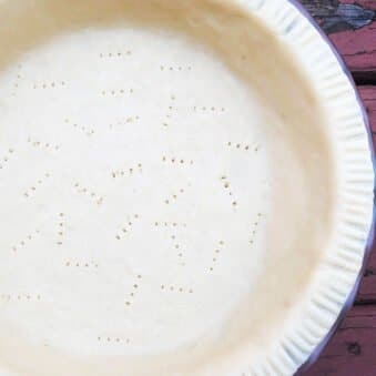 Easy Homemade Flaky Butter Pie Crust in Pie Dish on Rustic Red Wood Background