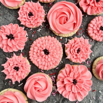 Easy Flower Cookies Decorated With Pink Buttercream Frosting on Rustic Gray Background.