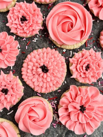 Easy Flower Cookies Decorated With Pink Buttercream Frosting on Rustic Gray Background.