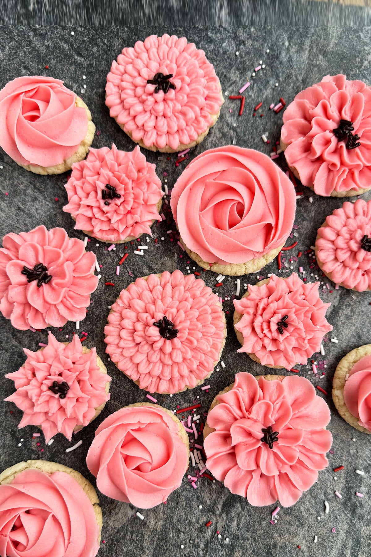 Easy Homemade Flower Cookies Decorated With Pink Buttercream Frosting on Rustic Gray Background.