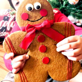 Kid Holding Jumbo Gingerbread Men Cookies With Christmas Decor in Background