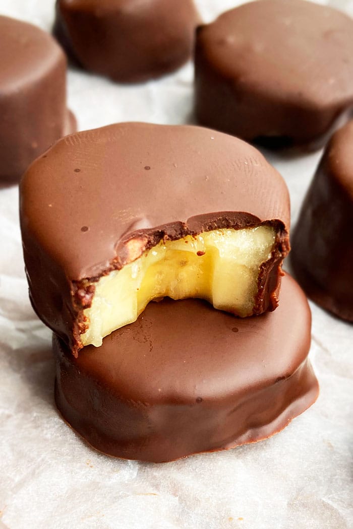 Stack of Frozen Chocolate Covered Bananas Bites on White Parchment Paper