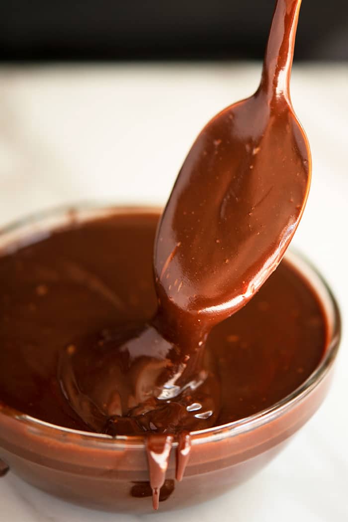 Spoonful of Best Chocolate Drip Over Glass Bowl on White Background