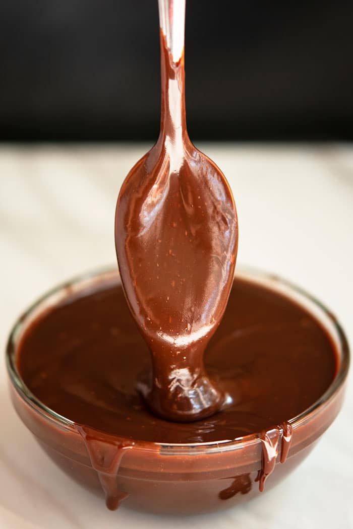 Easy Homemade Chocolate Ganache Dripping From Spoon into a Glass Bowl
