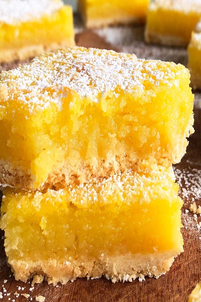 Stack of Two Easy Lemon Bars on Dark Wood Base With Partial Bite