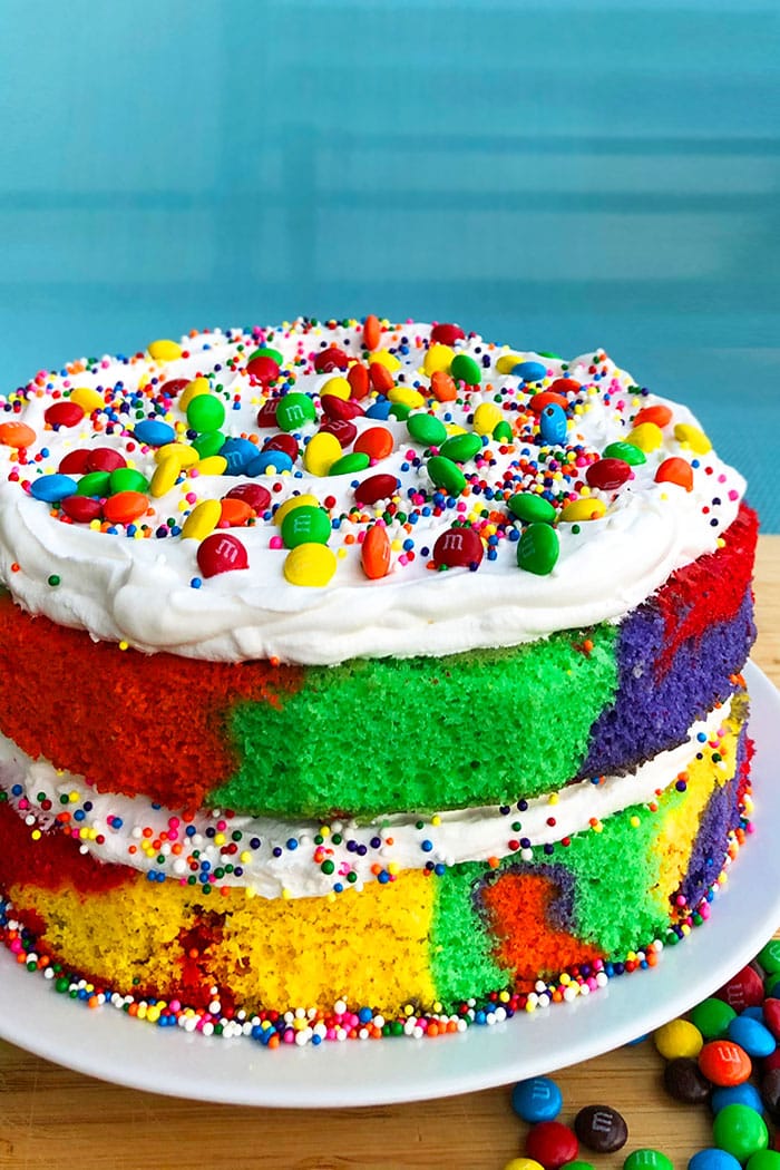 Rainbow Layer Cake on White Plate with Turquoise Background