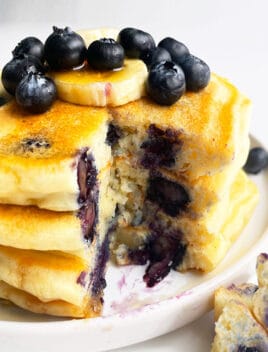 Stack of Easy Homemade Lemon Blueberry Pancakes in White Plate With One Slice Removed