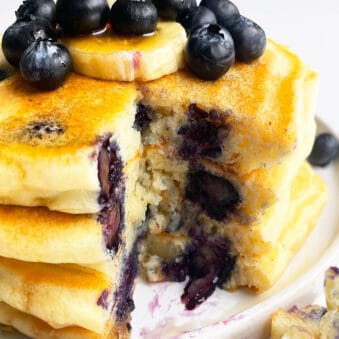 Stack of Easy Homemade Lemon Blueberry Pancakes in White Plate With One Slice Removed