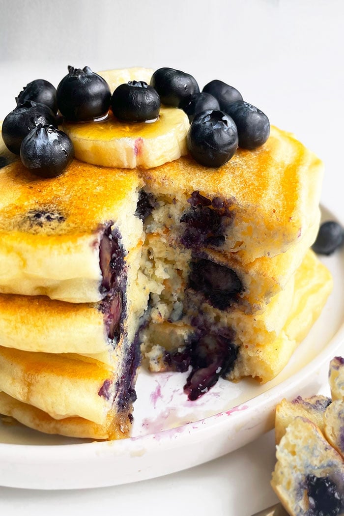 Stack of Easy Homemade Lemon Blueberry Pancakes in White Plate With One Slice Removed 