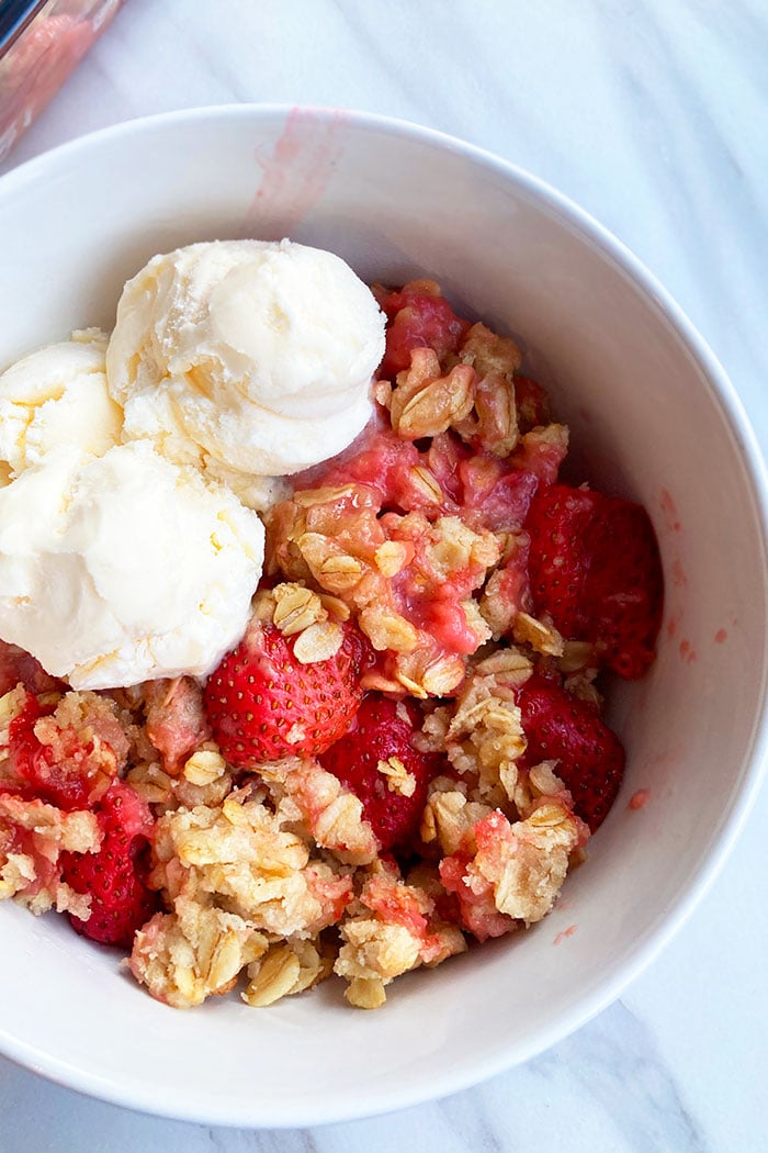 White Bowl Filled With Fresh Strawberries and Oats Crunch Topping and Vanilla Ice Cream- Overhead Shot