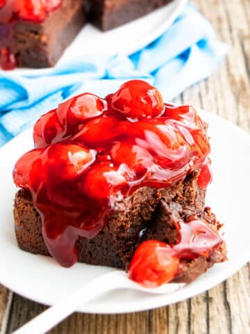 Easy Homemade Fudgy Gooey Brownies With Chocolate Ganache Frosting and Cherries on White Plate